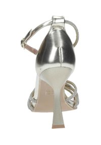 Sandal con tacco alto in argento metallizzato, con una sottile cinghia alla caviglia, cinturini incrociati decorati con strass e un tacco affusolato.