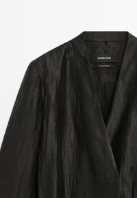 Schwarze Leinenblazer mit einem Reverskragen und strukturiertem Stoff. Das Etikett trägt "Massimo Dutti", hergestellt in Portugal.