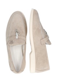 Mocasines de ante beige con costuras blancas y detalles de herrajes plateados. Punta redondeada y diseño de suela delgada y flexible. Textura lisa y plana.