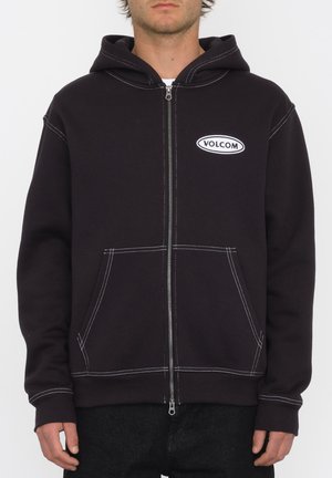 Haut à capuche zippé noir avec des accents de couture blanche et des poches avant ; comporte un logo "Volcom" brodé sur la poitrine ; tissu doux.