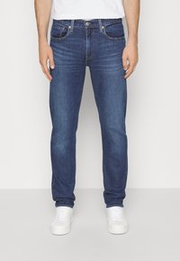 Džíny z tmavě modrého denimu s rovnými nohavicemi. Mají přední kapsy, zapínání na knoflíky a jemné vyblednutí látky.