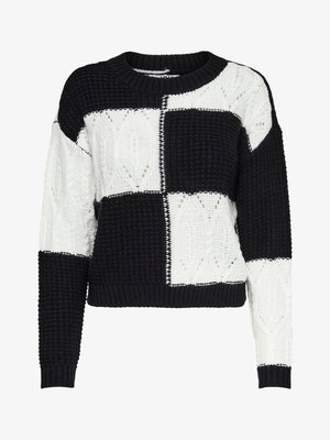 Strikket pullover med et sort og hvidt patchworkdesign, der har teksturerede mønstre og en rund hals, samt ribbede mansjetter og forneden.