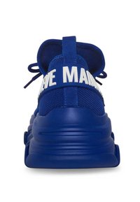 Blue athletic sneakers with a textured mesh upper, rubber sole, and a large white printed band that reads "MADE." Laces and padding at the heel.