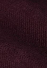 Gros plan d'un tissu violet foncé texturé, avec une apparence douce et veloutée et un subtil motif tissé.