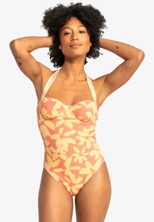 Én-delt badedragt med blomstermønster i bløde orange og gule nuancer, med halterneck-design og tekstureret stofdetalje.