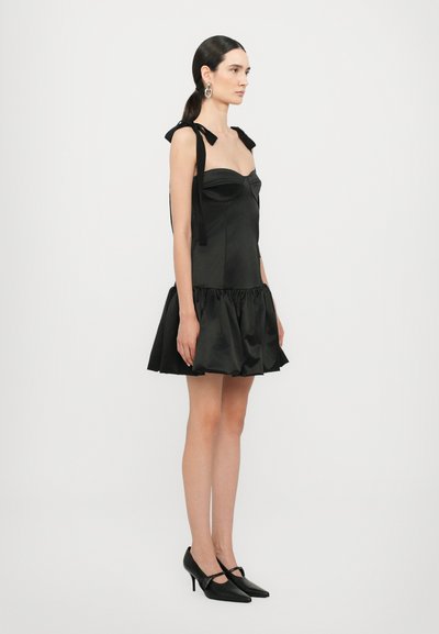 Vestido de sat�én negro con un corsé ajustado y un dobladillo con volantes. Presenta cintas en los hombros y se complementa con zapatos de tacón alto negros.