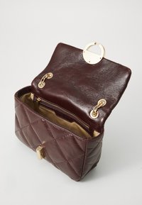 Sac à main en cuir bordeaux avec un motif matelassé, matériel doré, fermoir rond et doublure intérieure beige avec une poche zippée.