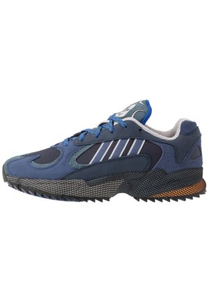 Niebiesko-czarny sportowy sneaker z niebieskimi sznurowadłami, biały wzór w paski po boku, teksturowana podeszwa oraz wyściełana szara wyściółka wewnętrzna.