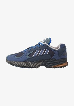 Baskets de sport bleues et noires avec lacets bleus, motif rayé blanc sur le côté, semelle texturée et doublure intérieure grise rembourrée.