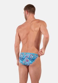 Herren-Schwimmbrieftaschen in Blau mit einem Paisleymuster, das mit rosa und grünen Akzenten verziert ist. Hergestellt aus glattem Stoff, entworfen für eine enge Passform.