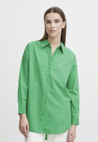 Green button-up shirt with a collar, long sleeves, and a relaxed fit. Made from a smooth, lightweight fabric with a solid color.