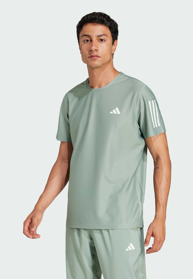 Camiseta atlética verde claro hecha de una tela suave. Presenta el logo blanco de Adidas y tres rayas verticales en la manga izquierda.