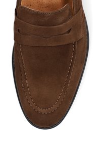 Brązowe zamszowe loafersy z zaokrąglonym noskiem, ozdobnym stębnowaniem i podniesionym wzorem szwu. Posiadają czarną gumową podeszwę i gładką teksturę.