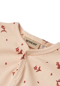 Miękki beżowy prążkowany body dla niemowląt z czerwoną kwiatową nadruką, zatrzaski z przodu i metka marki "WHEAT" przy kołnierzyku.