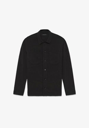 Črna majica z dolgimi rokavi, izdelana iz tkanine gladke teksture, s dvema žepoma na prsih in zapenjanjem s kosi po sprednji strani.