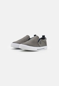 Chaussures slip-on en cuir gris avec une texture lisse, semelle en caoutchouc blanc et accents élastiques bleu marine sur les côtés pour un enfilage facile.