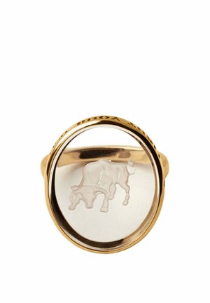 Anillo de oro con una parte superior de vidrio circular transparente que presenta una imagen grabada de una vaca pastando en el centro.