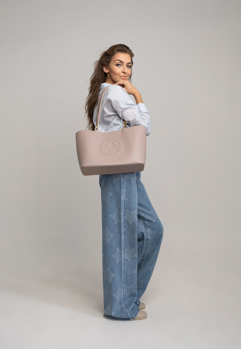 Borsa tote rosa chiaro realizzata in materiale liscio, con forma arrotondata, logo impresso sul davanti e hardware dorato.