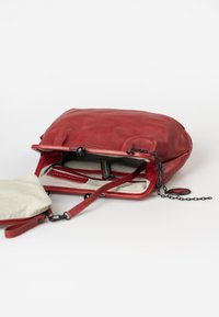Rote Lederhandtasche mit weicher Textur, offene Oberseite, innenliegende Reißverschlusstaschen und abnehmbarer Kettenriemen. Innen mit gestreiftem Stoff ausgekleidet.