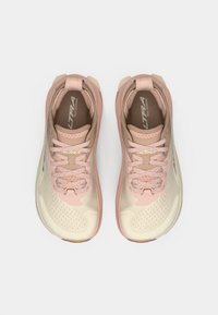 Sapatos de corrida em trilha em rosa claro e bege. Apresentam um cabedal em malha com perfurações, atacadores planos e um design de sola flexível.