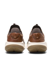 Sneaker in pelle marrone e tessuto grigio con una suola intermedia bianca e suola in gomma testurizzata, dotati di un manico sul retro.