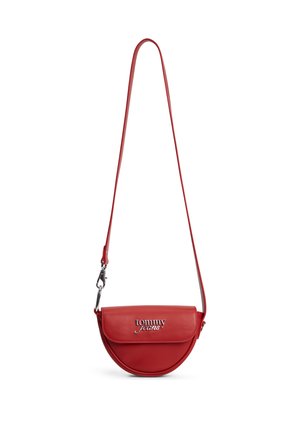 Bolso bandolera de cuero rojo con forma de media luna, con correa larga y logo plateado "tommy jeans" en la solapa frontal.