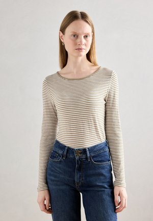 Stripet langermet skjorte i beige og kremfarger, med båtjakke og tettsittende design, kombinert med høy midje blå denimjeans.