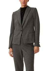Dopasowana marynarka w czarno-białą kratę houndstooth. Posiada zapięcie na jeden guzik, klapy z wycięciem oraz dwie przednie kieszenie. Teksturowany materiał.