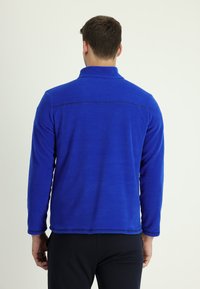 Pullover in pile blu con collo alto e maniche lunghe. Presenta cuciture piatte e una texture liscia. Senza loghi o motivi visibili.