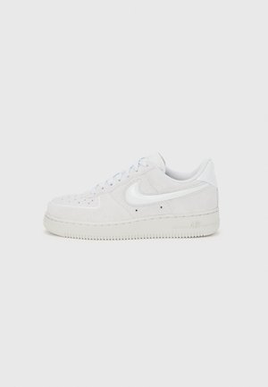 Biały zamszowy sneaker Nike Air Force 1 z teksturowanym wykończeniem, zaokrąglonym noskiem i kontrastującym białym akcentem logo, wyposażony w gumową podeszwę.