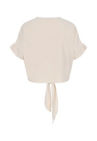 Top court beige à manches courtes avec poignets à volants et liens pendants au centre du dos.