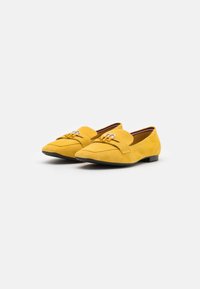 Mocassini in suede giallo con suola piatta, dotati di una fascia decorativa frontale e hardware in argento. Punta arrotondata e design minimalista.