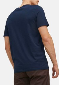 Granatowa koszulka z krótkim rękawem, wykonana z miękkiej bawełny, z okrągłym dekoltem i dopasowanym krojem o gładkiej fakturze.