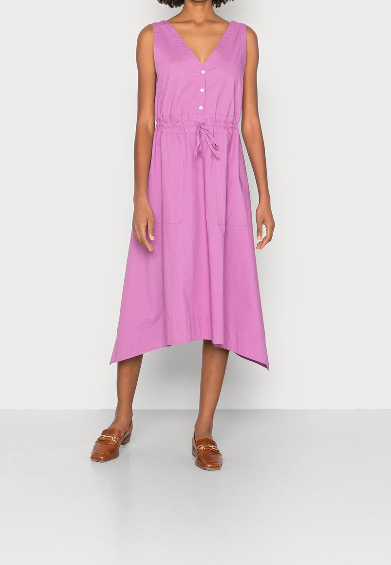 Robe violette sans manches avec un col en V, des boutons à l'avant, une taille cintrée et deux poches. Texture lisse avec un ourlet asymétrique légèrement évasé.