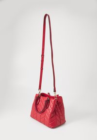 Röd vadderad handväska med en strukturerad form, dubbla ovandelshandtag och en justerbar axelrem. Guldtonat hårdvara ger en extra dimension till designen.