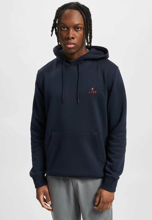 Navy blue hoodie in soft fabric features a kangaroo pocket, drawstring hood, and small red "JJ90" logo on the chest.