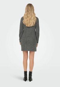 Abito maglione grigio a maglia con maniche lunghe, orlo a coste e vestibilità comoda, abbinato a stivaletti neri alla caviglia.