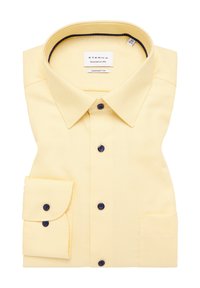 Camicia gialla a quadrati con colletto a punta, bottoni blu scuro e taschino sul lato sinistro del petto. Realizzata in tessuto leggero. Marchio ETERNA visibile.