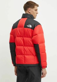 Giacca a vento rossa e nera con design trapuntato, colletto alto e logo in gomma sulla spalla. Polsini e orlo elasticizzati.