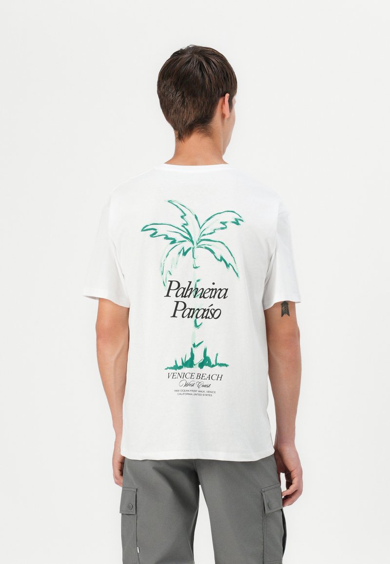 Balto medvilninio marškinėliai su žaliu palmės medžio grafika ir tekstu ant nugaros, kur yra "Palmeira Paraíso" ir "Venice Beach".