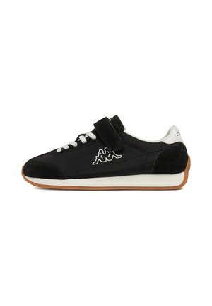 Zwart-witte lage sneaker met witte veters, een klittenbandsluiting, een wit logo aan de zijkant en een bruine zool.