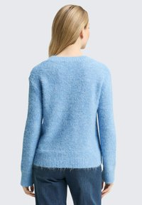 Hellblau gestrickter Pullover mit einer strukturierten, flauschigen Optik. Verfügt über einen gerippten Saum und Bündchen, einen runden Ausschnitt und lange Ärmel.