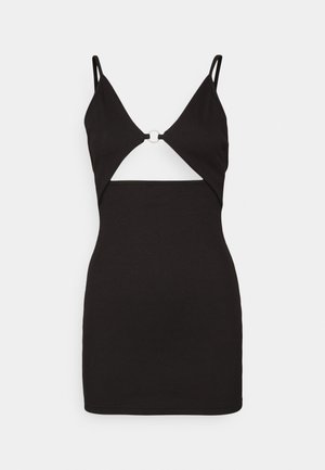 Vestido preto sem mangas com um design recortado, apresentando um detalhe metálico circular no peito, feito de material canelado.