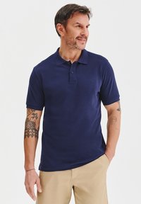 Granatowa koszulka polo z krótkim rękawem, z zapięciem na trzy guziki i subtelnym logo. Gładka tekstura, casualowy design i dopasowany krój.