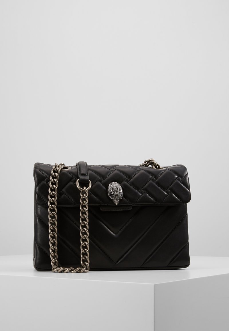 Borsa a tracolla in pelle trapuntata nera con catena argentata e chiusura decorativa. Presenta motivi a zig-zag e una finitura liscia.