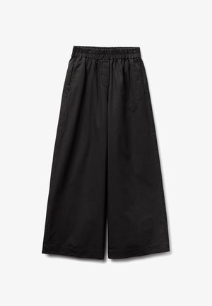 Pantalones de pierna ancha negros, confeccionados en tejido ligero, con cintura elástica, bolsillos laterales y una textura suave.