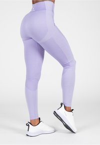 Paarse leggings van rekbaar materiaal, met een hoge tailleband, textuurpanelen en een taps toelopend ontwerp. Gecombineerd met witte sneakers.