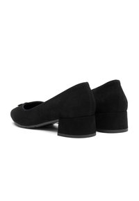 Scarpe da donna in suede nero con tacco basso a blocco e punta rotonda, viste da un'angolazione laterale posteriore su uno sfondo bianco.