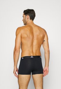 Svarta bomullsboxer med en åtsittande design, accentuerade av en svart midjeband med tre vita Adidas-sträck och logo.