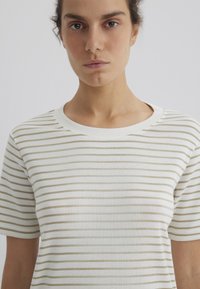 Gestreiftes T-Shirt in Creme mit horizontalen hellbraunen Streifen. Es hat einen Rundhalsausschnitt und kurze Ärmel und besteht aus einem weichen, glatten Stoff.
